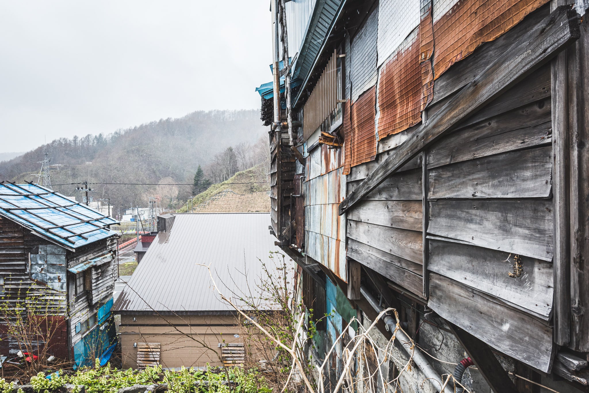 Hill View at Streetscapes of Yubari, a view from the side of a house looking out over the hills of Yubari.