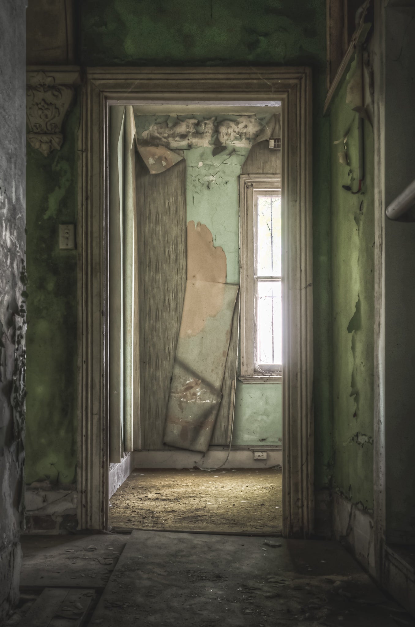 Bar Keepers Office at Terminus Hotel, light spills through a tall window at the end of the hallway, catching on dust.