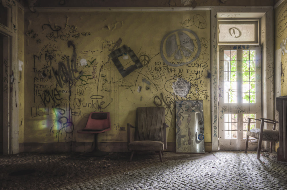 Common Room at Terminus Hotel, a faded yellow wall covered floor to ceiling in graffiti and marker scrawl.