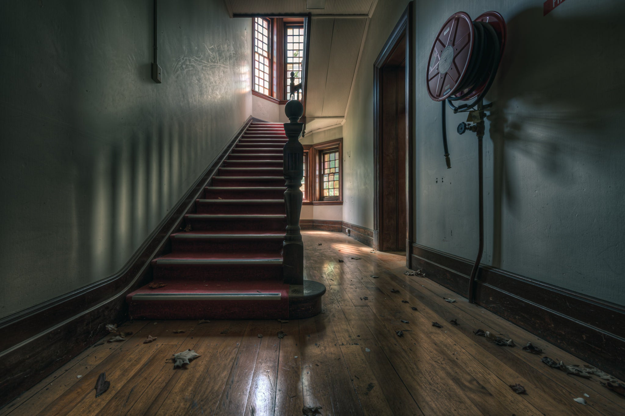 Administration Staircase at The Asylum, a carpeted staircase rises from a ground-floor hallway, its turned newel post.