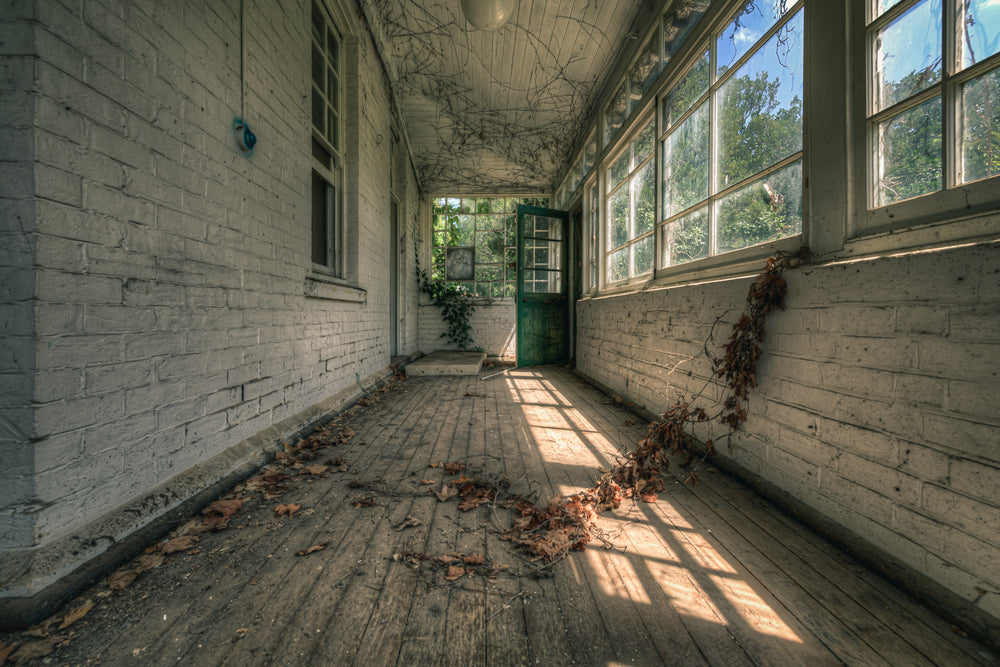 Balcony at The Asylum, a narrow enclosed verandah runs between white-painted brick walls.