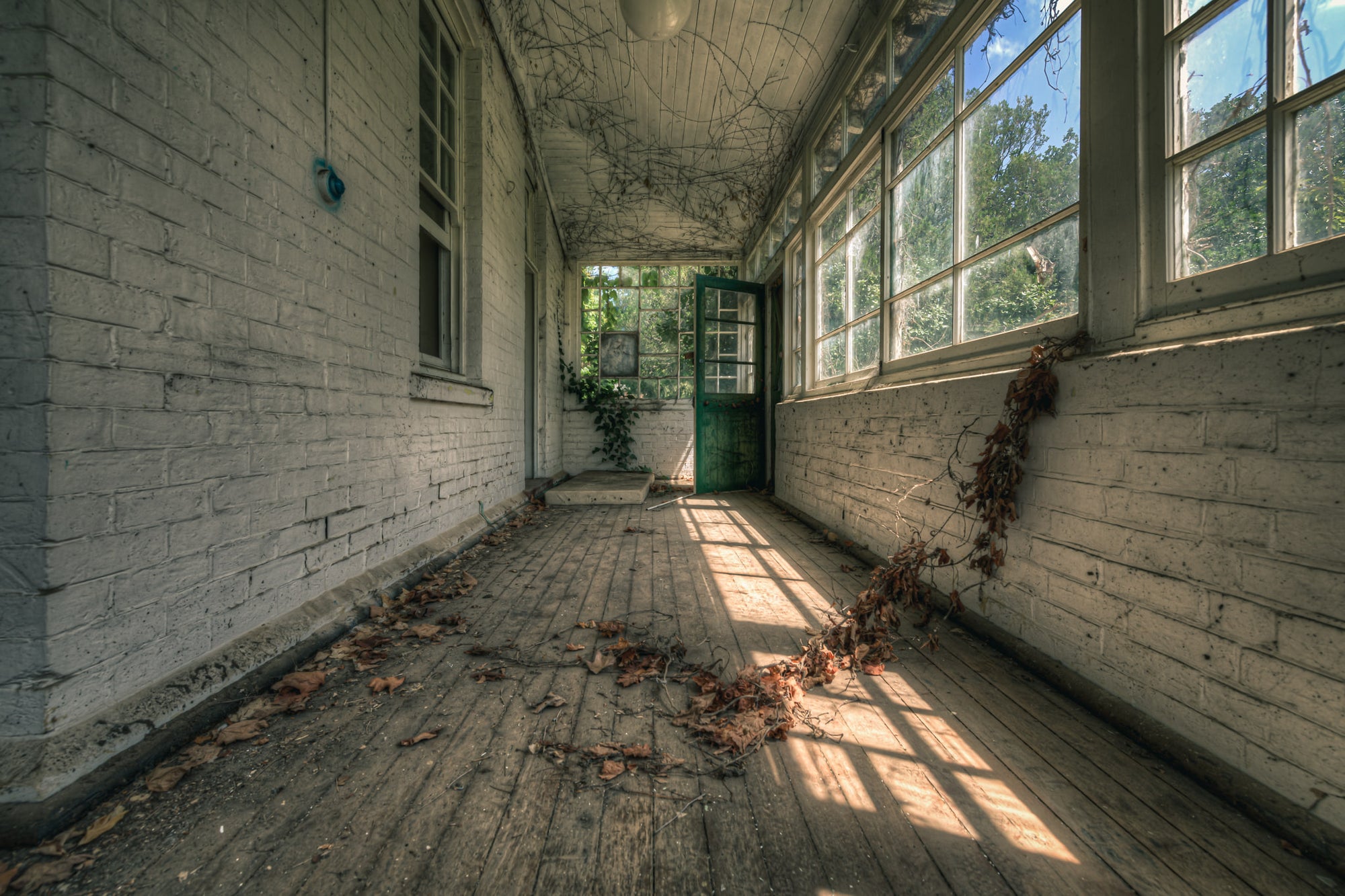 Balcony at The Asylum, a narrow enclosed verandah runs between white-painted brick walls.