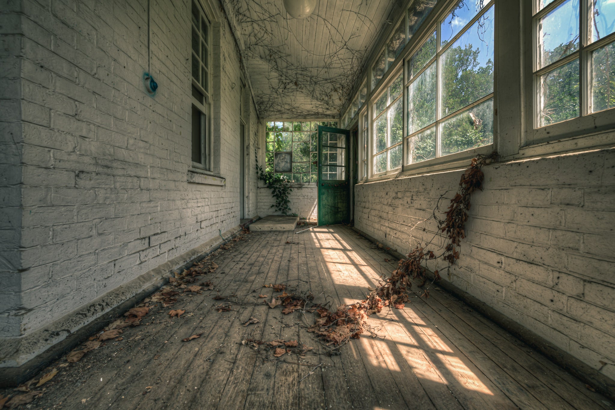 Balcony at The Asylum, a narrow enclosed verandah runs between white-painted brick walls.