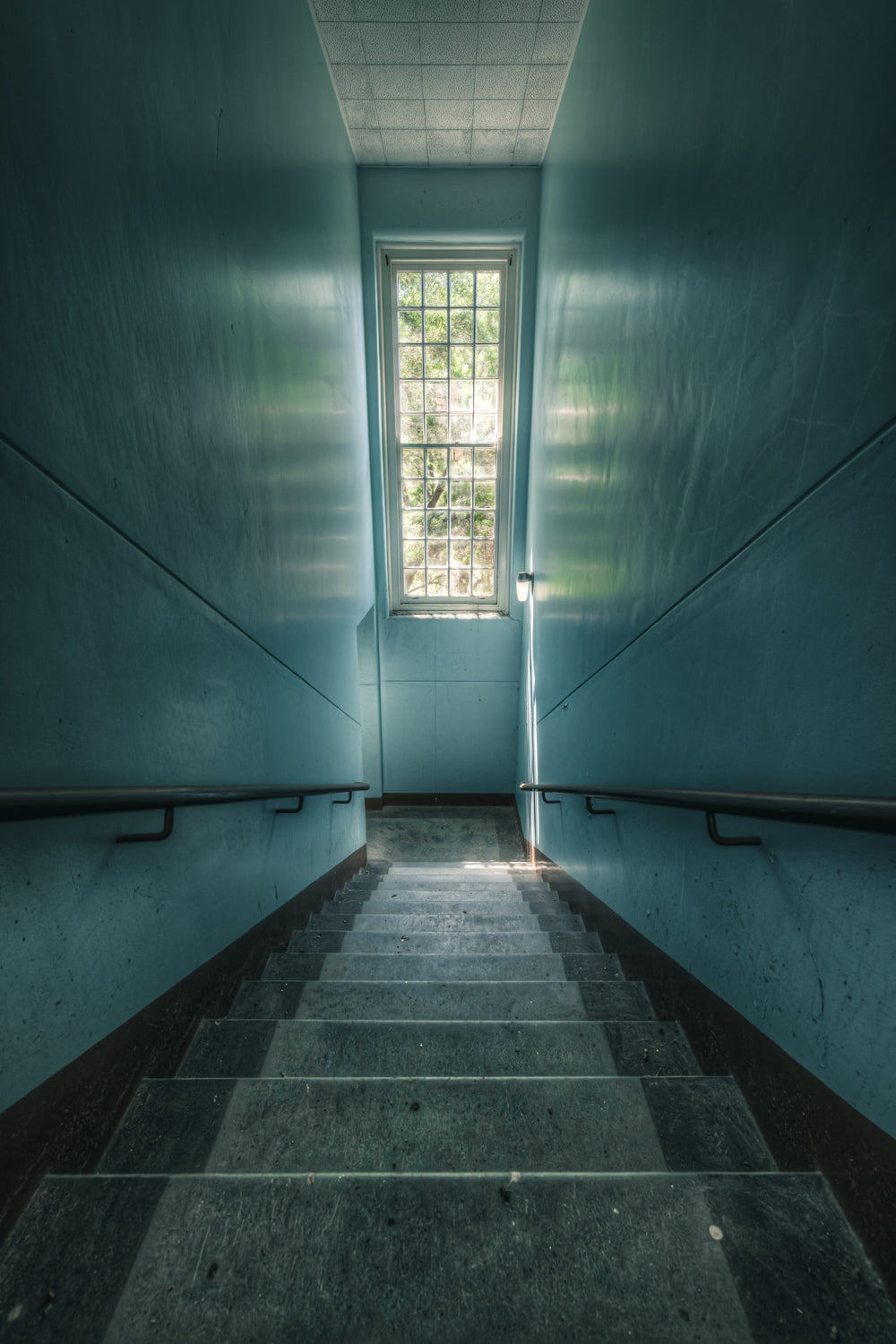 Blue Descent at The Asylum, a narrow stairwell descends between teal-painted walls.