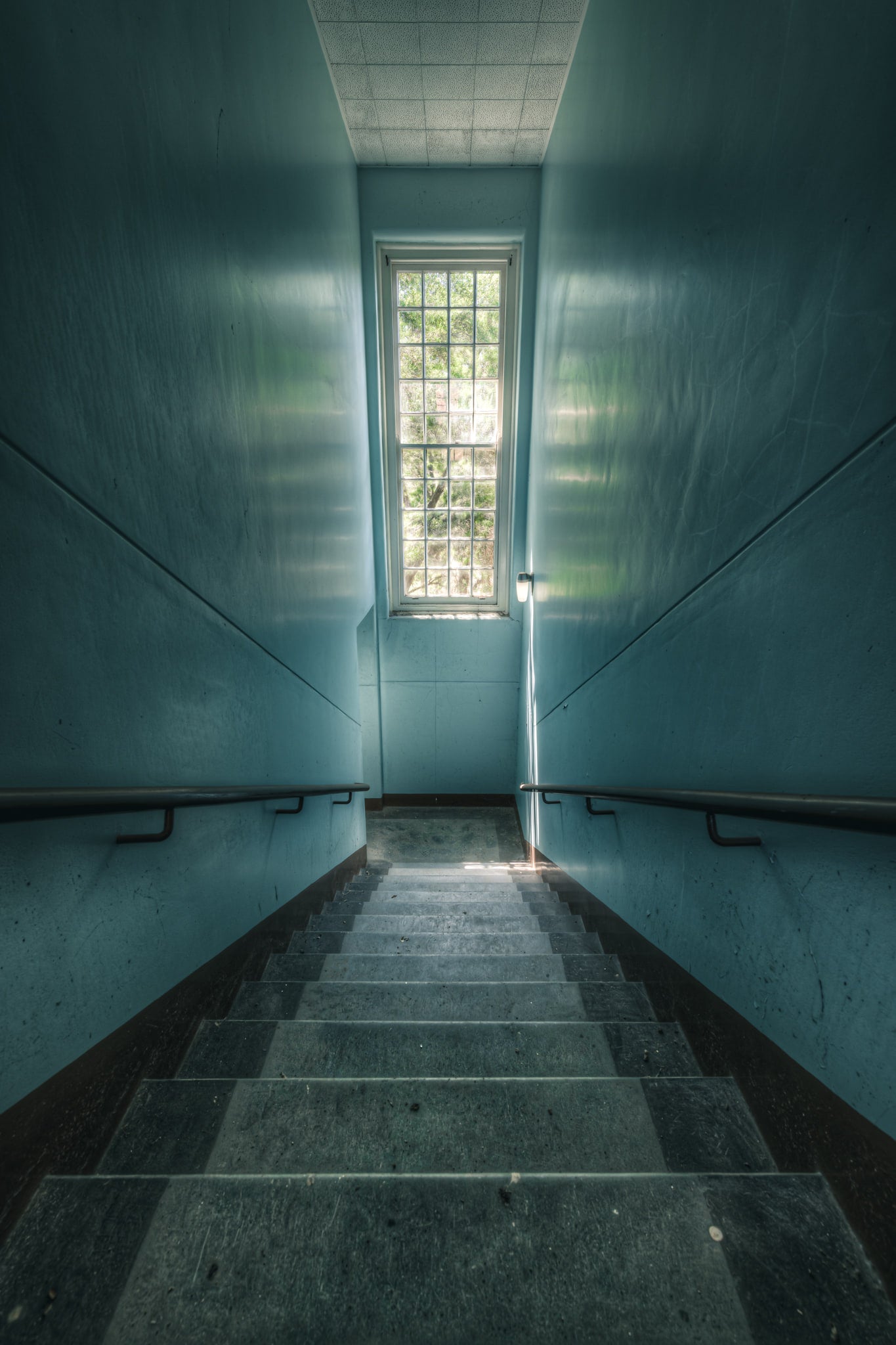 Blue Descent at The Asylum, a narrow stairwell descends between teal-painted walls.