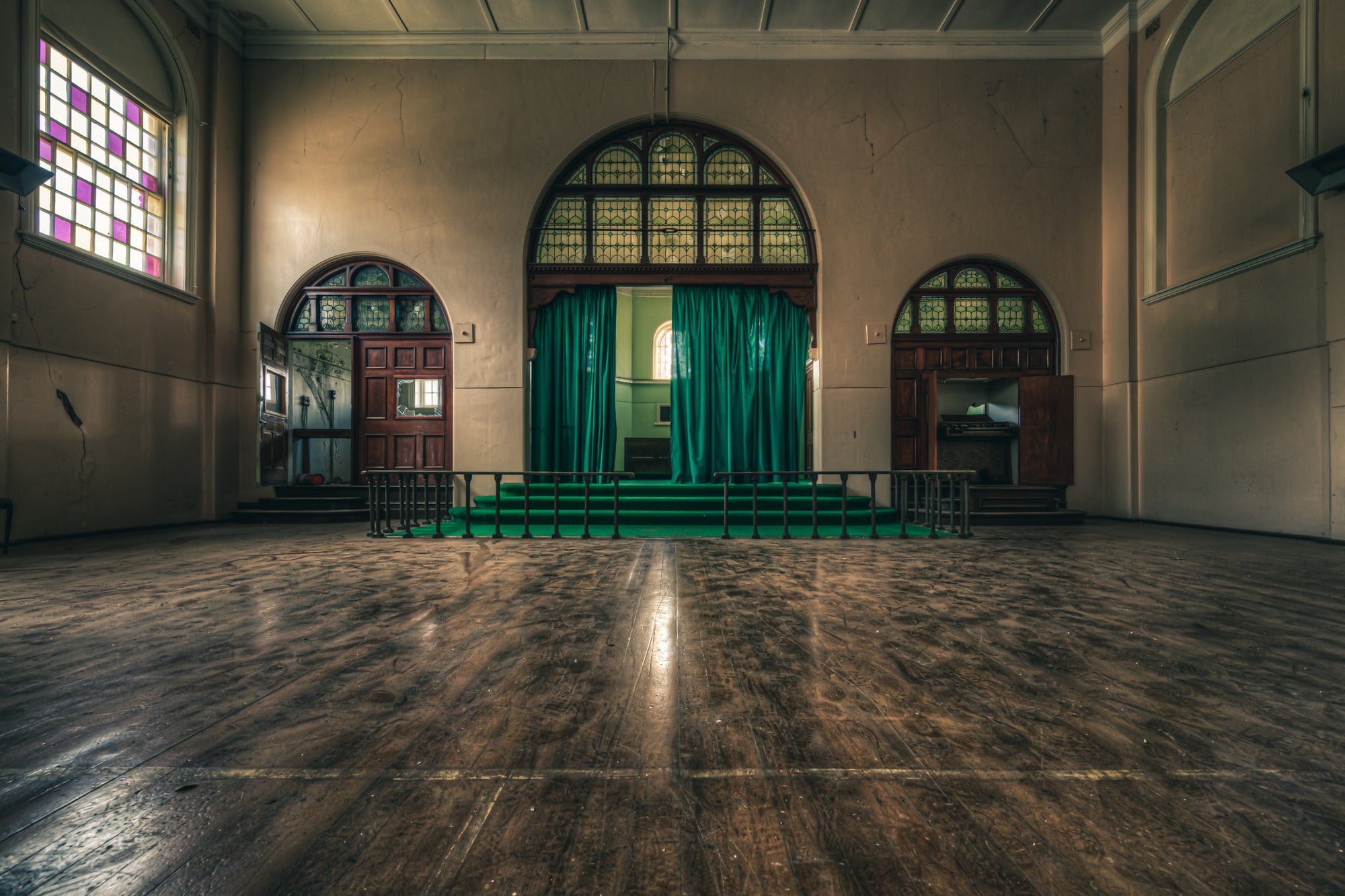 Chapel at The Asylum, a large hall with worn timber floorboards stretching toward a raised stage.