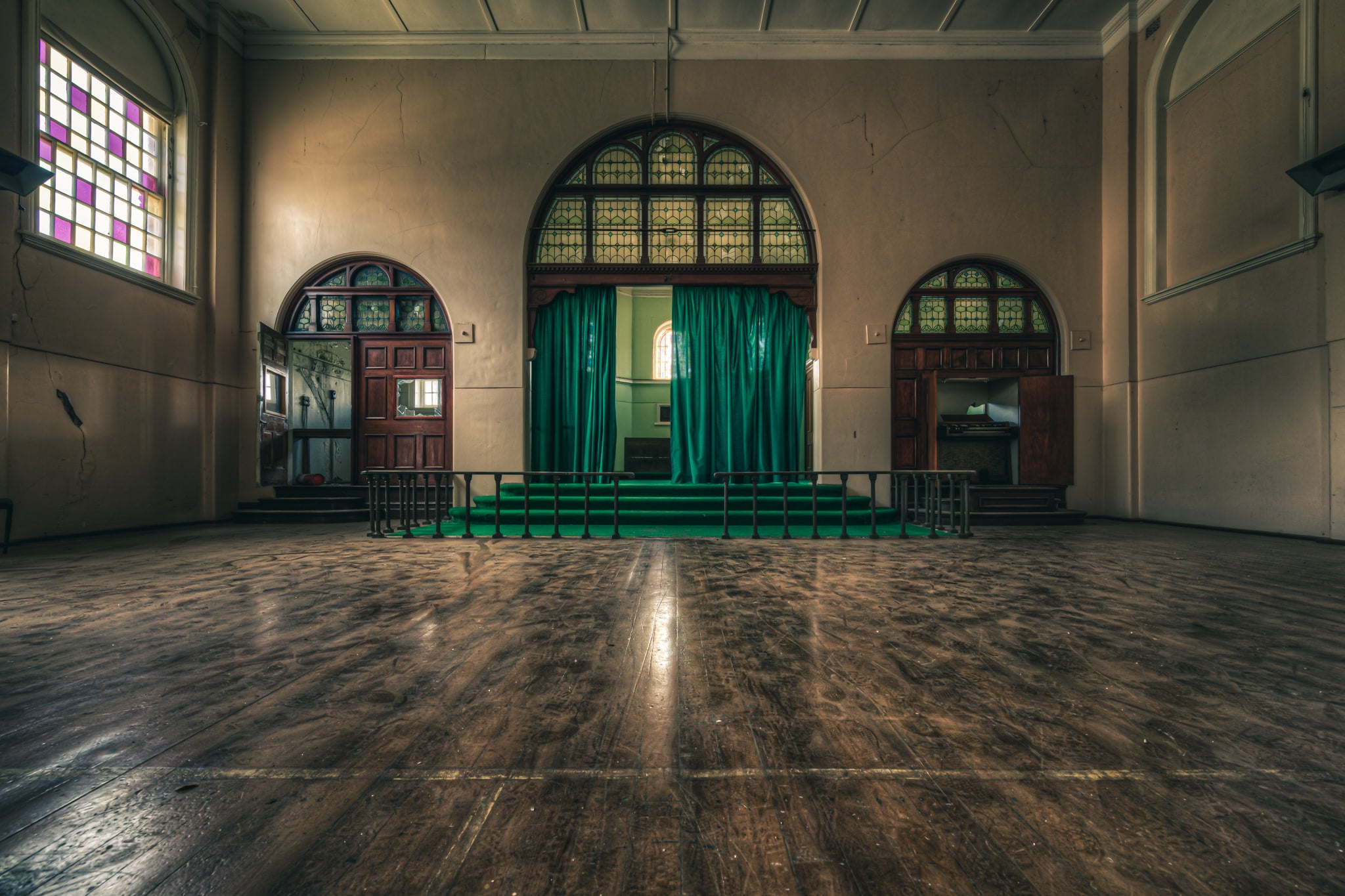 Chapel at The Asylum, a large hall with worn timber floorboards stretching toward a raised stage.
