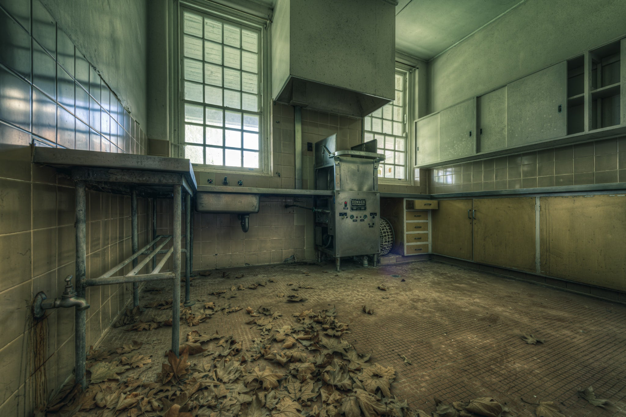 Cleaning Kitchen at The Asylum, dead leaves cover the tiled floor in thick drifts.