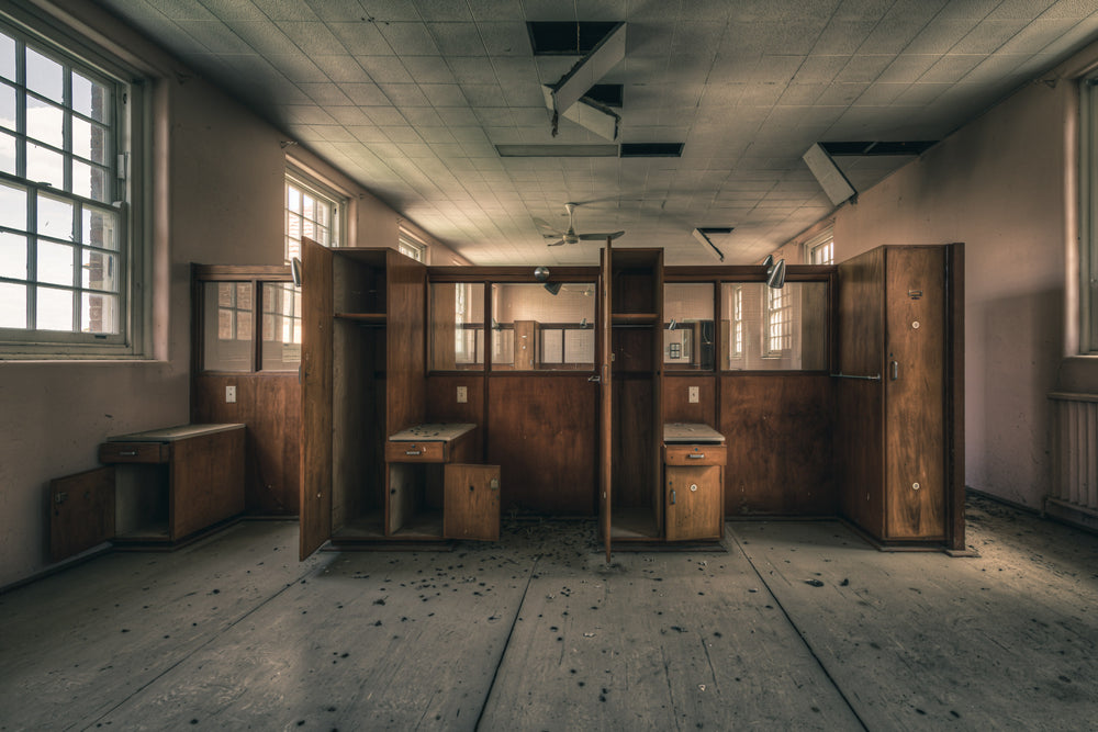 Divide at The Asylum, timber wardrobes and bedside cabinets stand open in two rows, dividing the room into narrow cubicles.