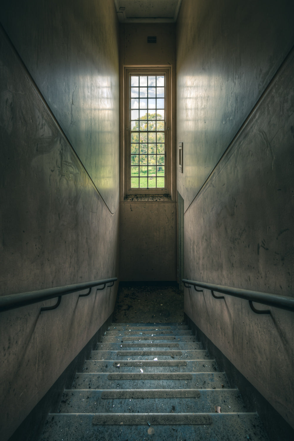 Glimmer at The Asylum, a concrete stairwell descends between narrow walls.