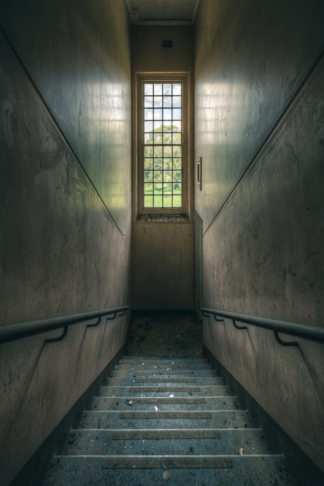 Glimmer at The Asylum, a concrete stairwell descends between narrow walls.