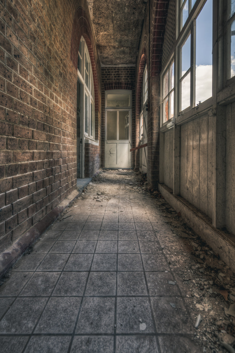 In Between at The Asylum, a narrow corridor runs between a brick wall and a timber-panelled enclosure.