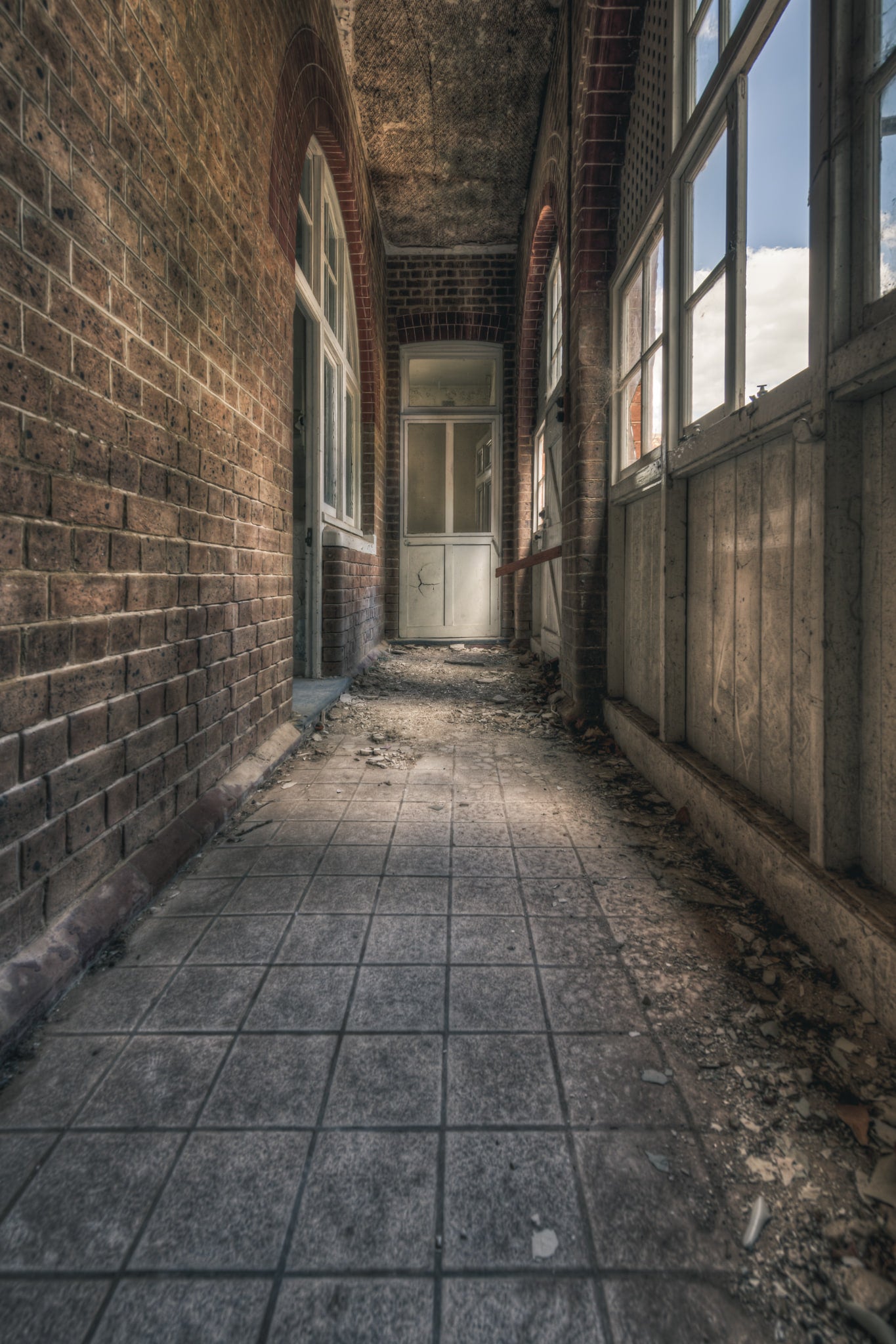 In Between at The Asylum, a narrow corridor runs between a brick wall and a timber-panelled enclosure.
