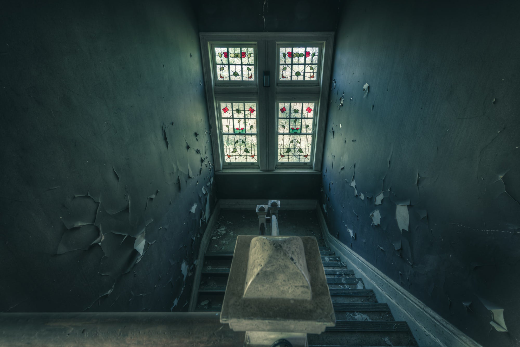 Leadlight Stairs at The Asylum, a stairwell narrows toward a four-panel leadlight window.