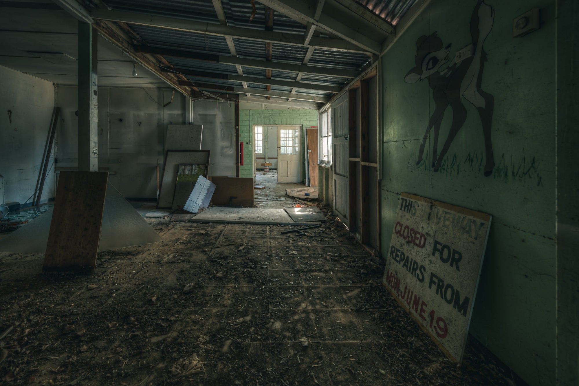 Mixed Signals at The Asylum, a long corridor stretches toward a green-tiled doorway at the far end.