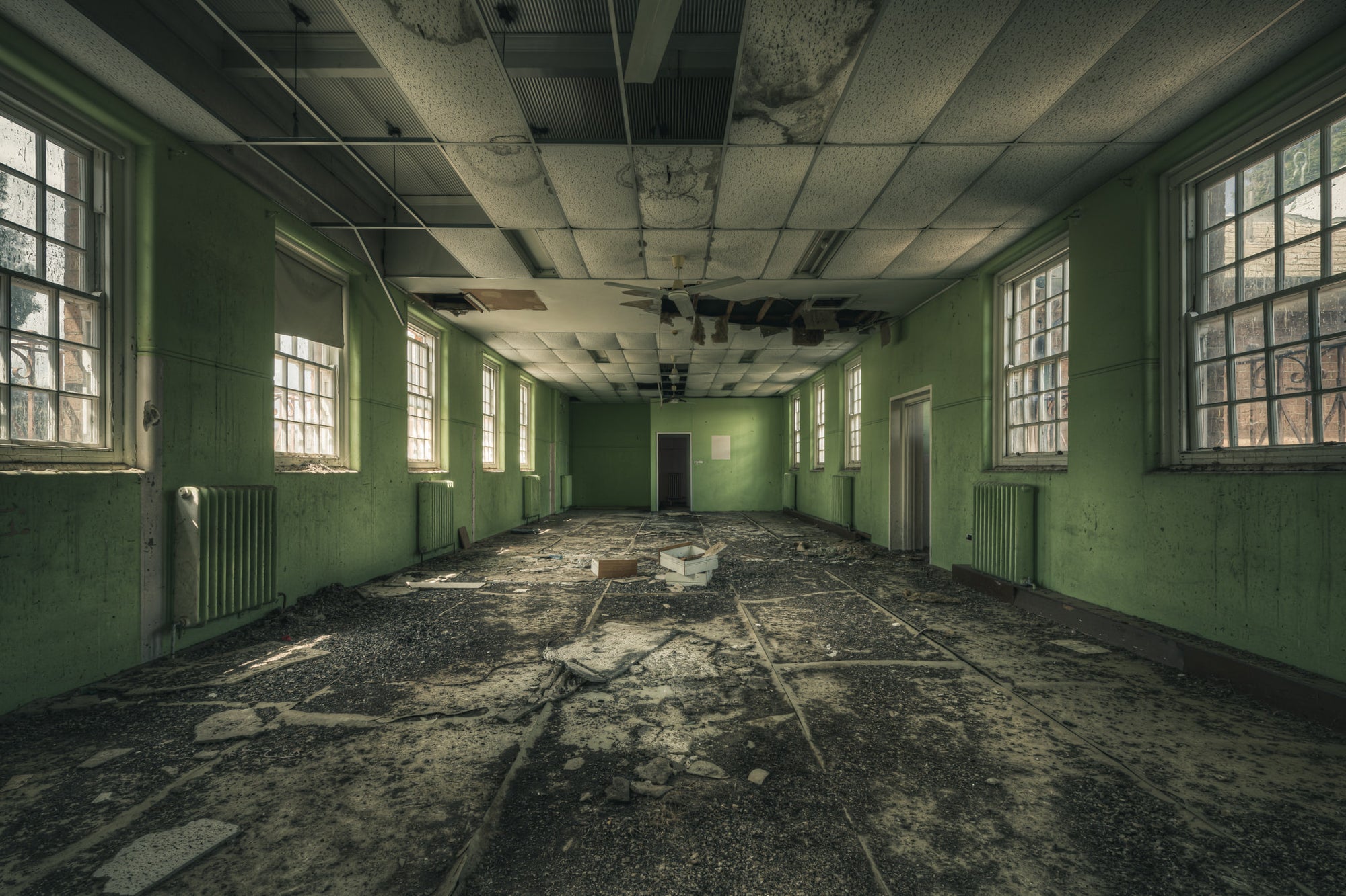 Narrow Green Room at The Asylum, a long rectangular room stretches toward a single door at the far end.