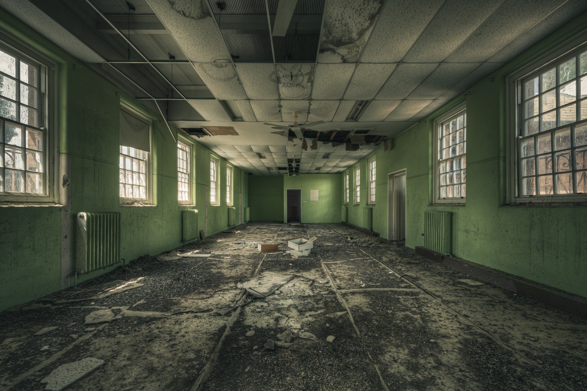 Narrow Green Room at The Asylum, a long rectangular room stretches toward a single door at the far end.