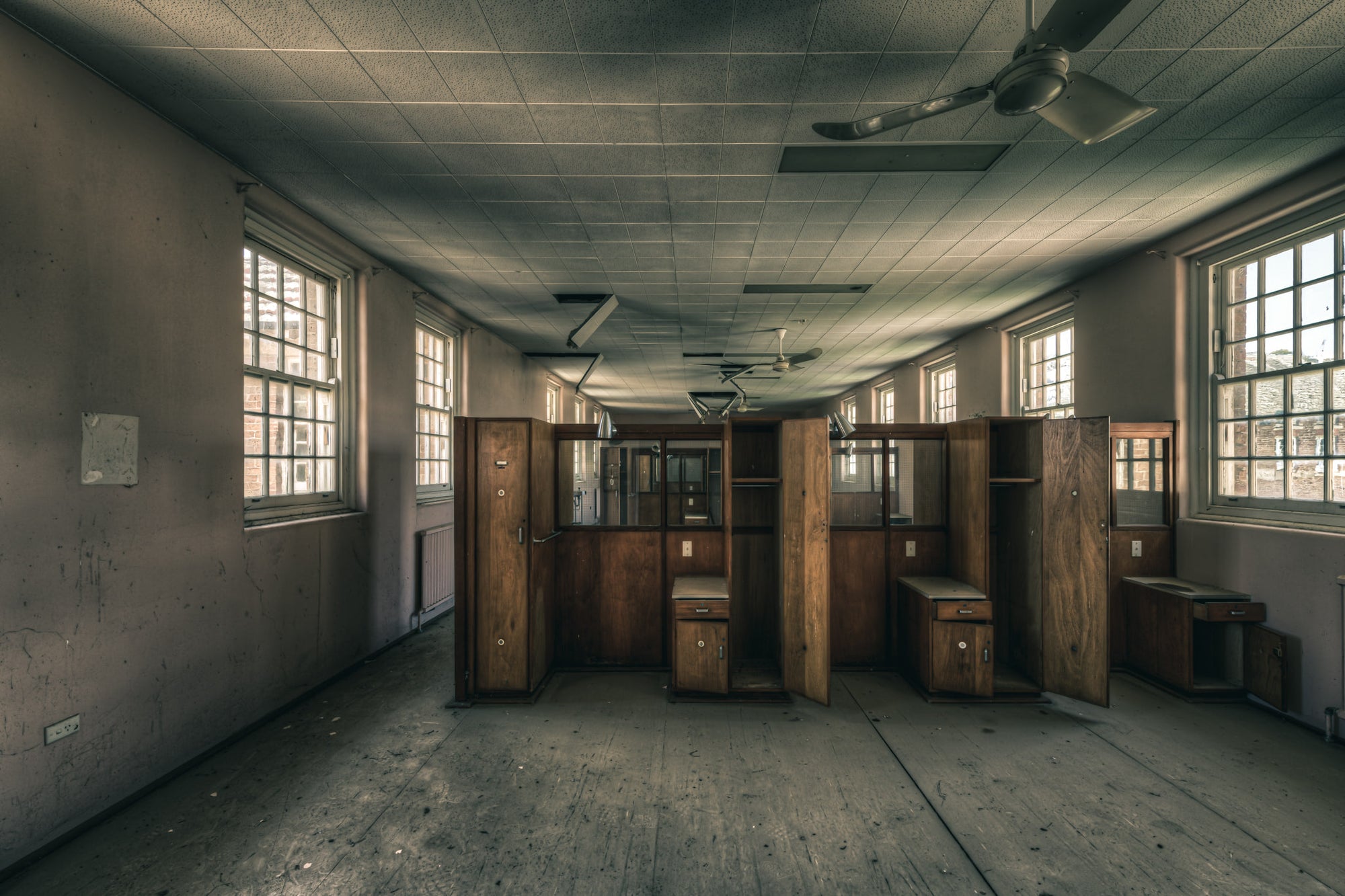 Patient Partitions at The Asylum, timber partitions stand clustered in the centre of a long ward.