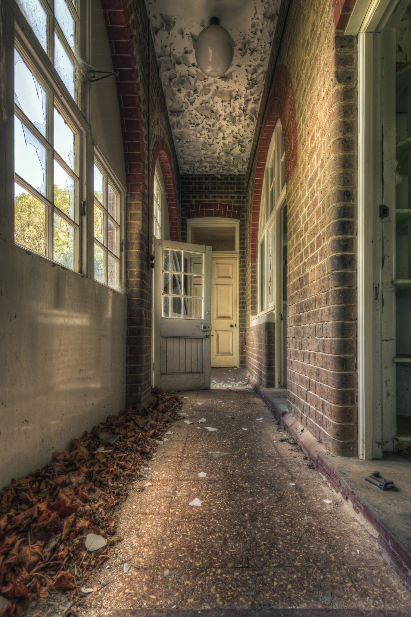 Pebblecrete Pavers at The Asylum, a narrow corridor runs between red brick columns and a rendered half-wall.