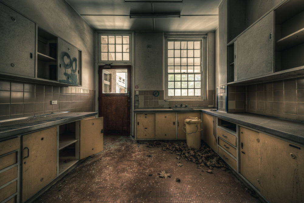 Prep Kitchen at The Asylum, a U-shaped bench runs the length of the room, laminate doors hanging open on empty cupboards.