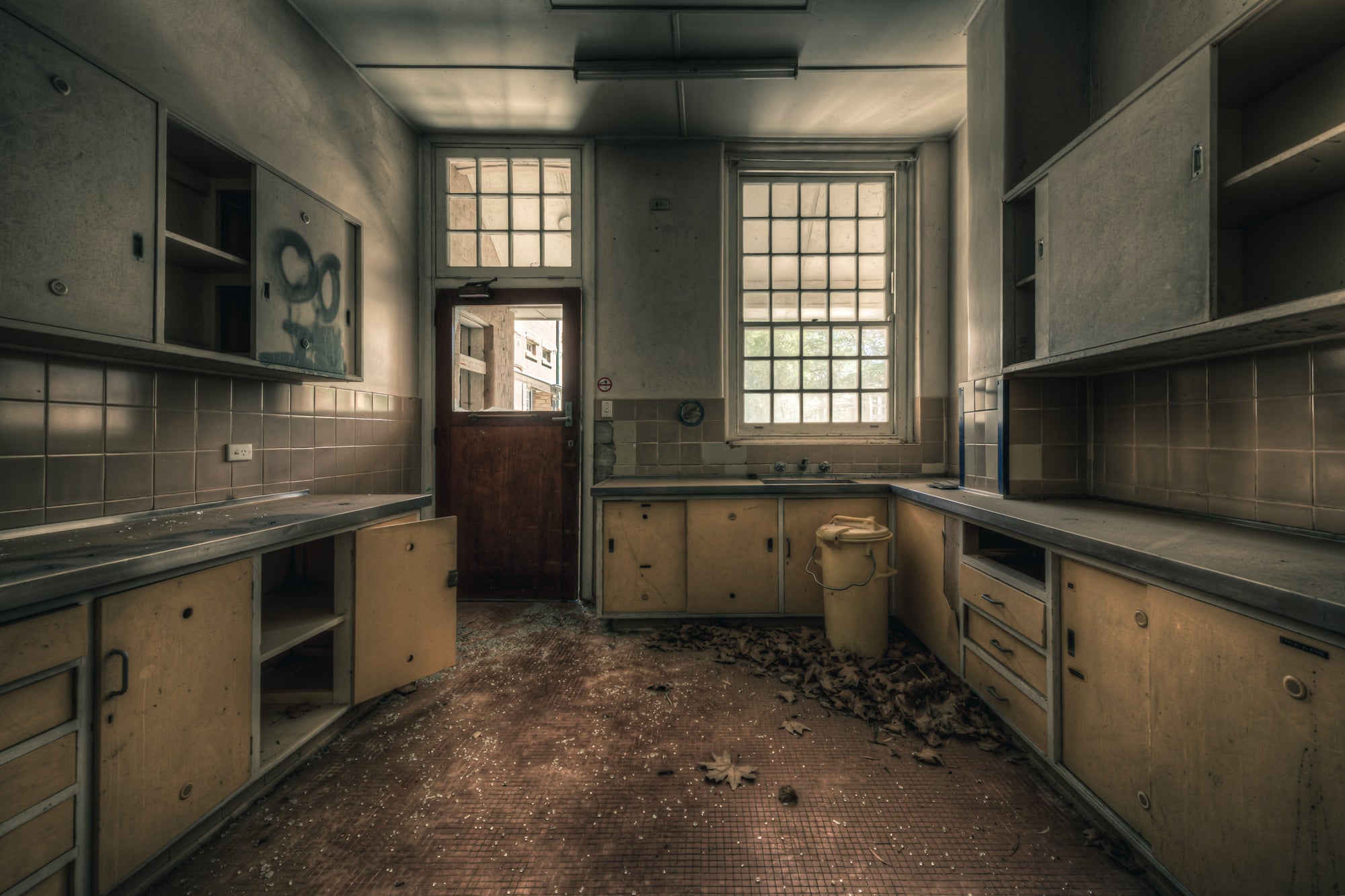 Prep Kitchen at The Asylum, a U-shaped bench runs the length of the room, laminate doors hanging open on empty cupboards.