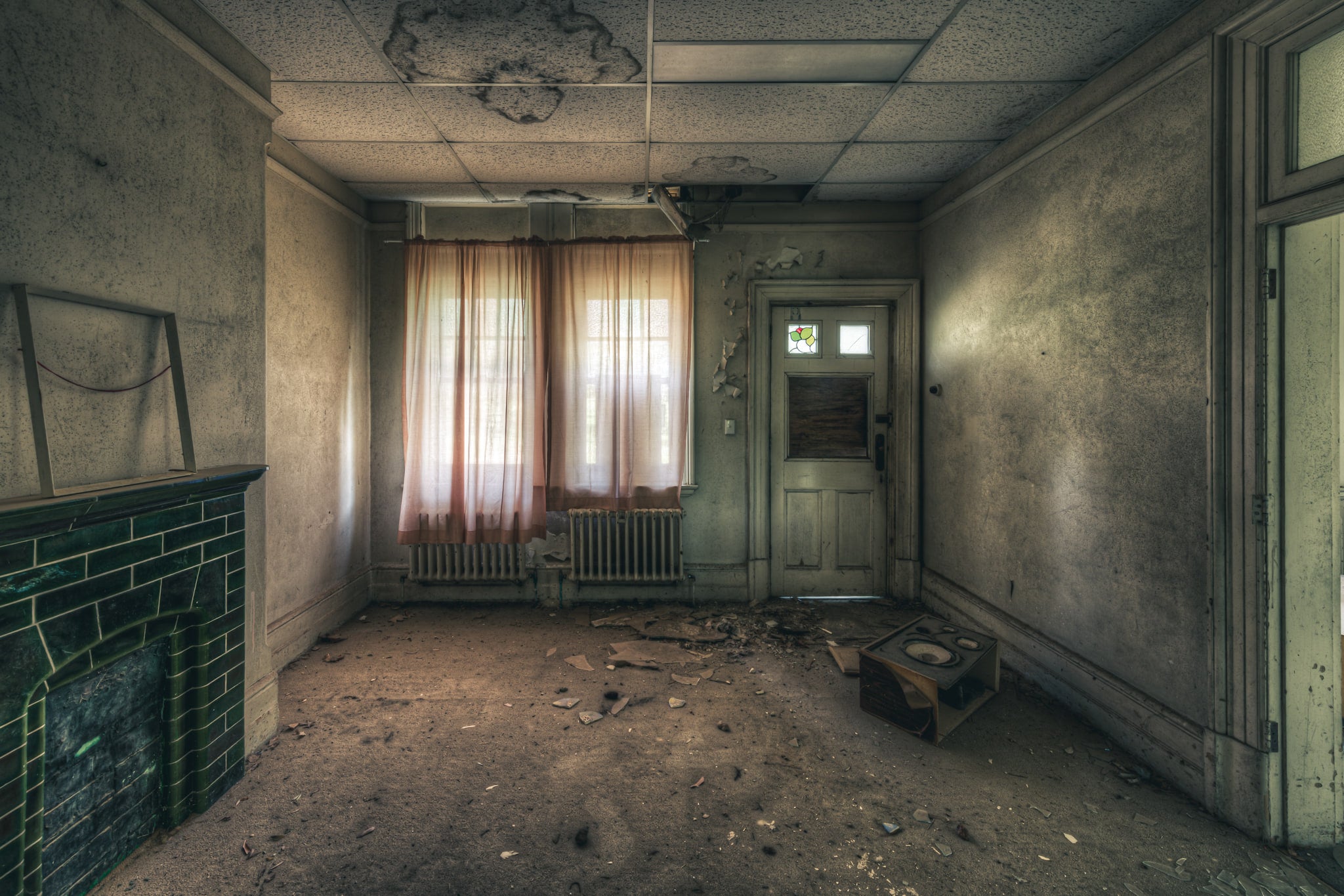 Recreation Room at The Asylum, faded pink curtains filter grey light through a pair of windows.