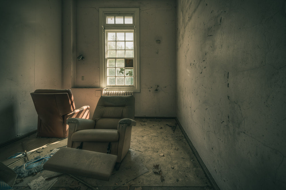 Reflective at The Asylum, two recliner chairs sit angled toward a tall multi-pane window.