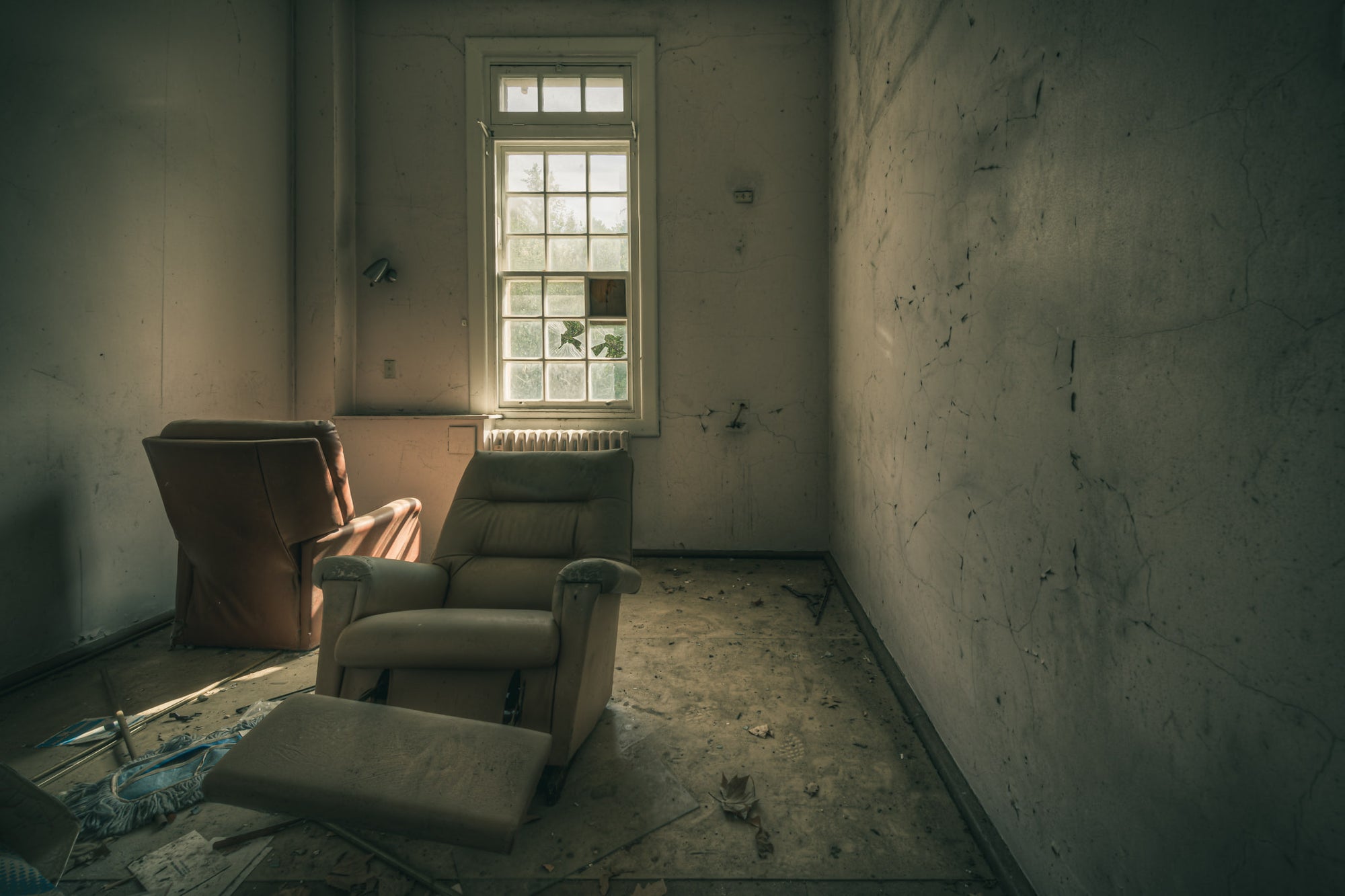 Reflective at The Asylum, two recliner chairs sit angled toward a tall multi-pane window.