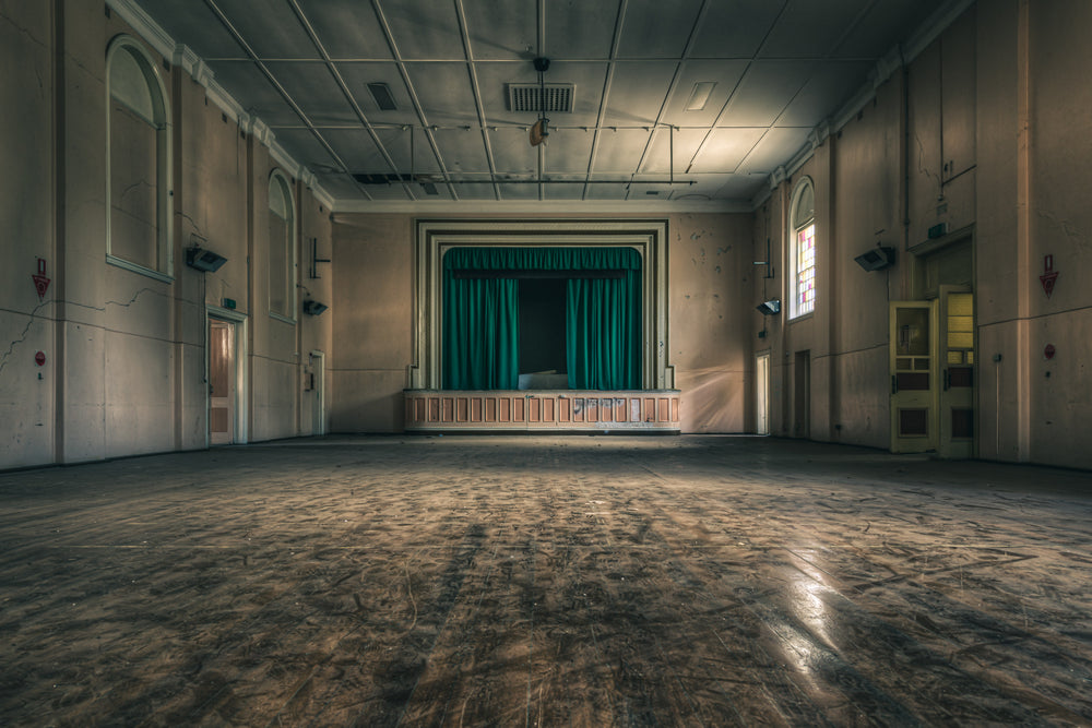 Setting the Stage at The Asylum, a green curtain hangs closed across the proscenium stage.