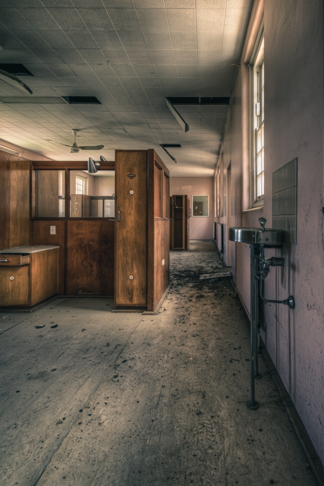 Slipping Away at The Asylum, a stainless steel basin hangs from exposed plumbing on the corridor wall.