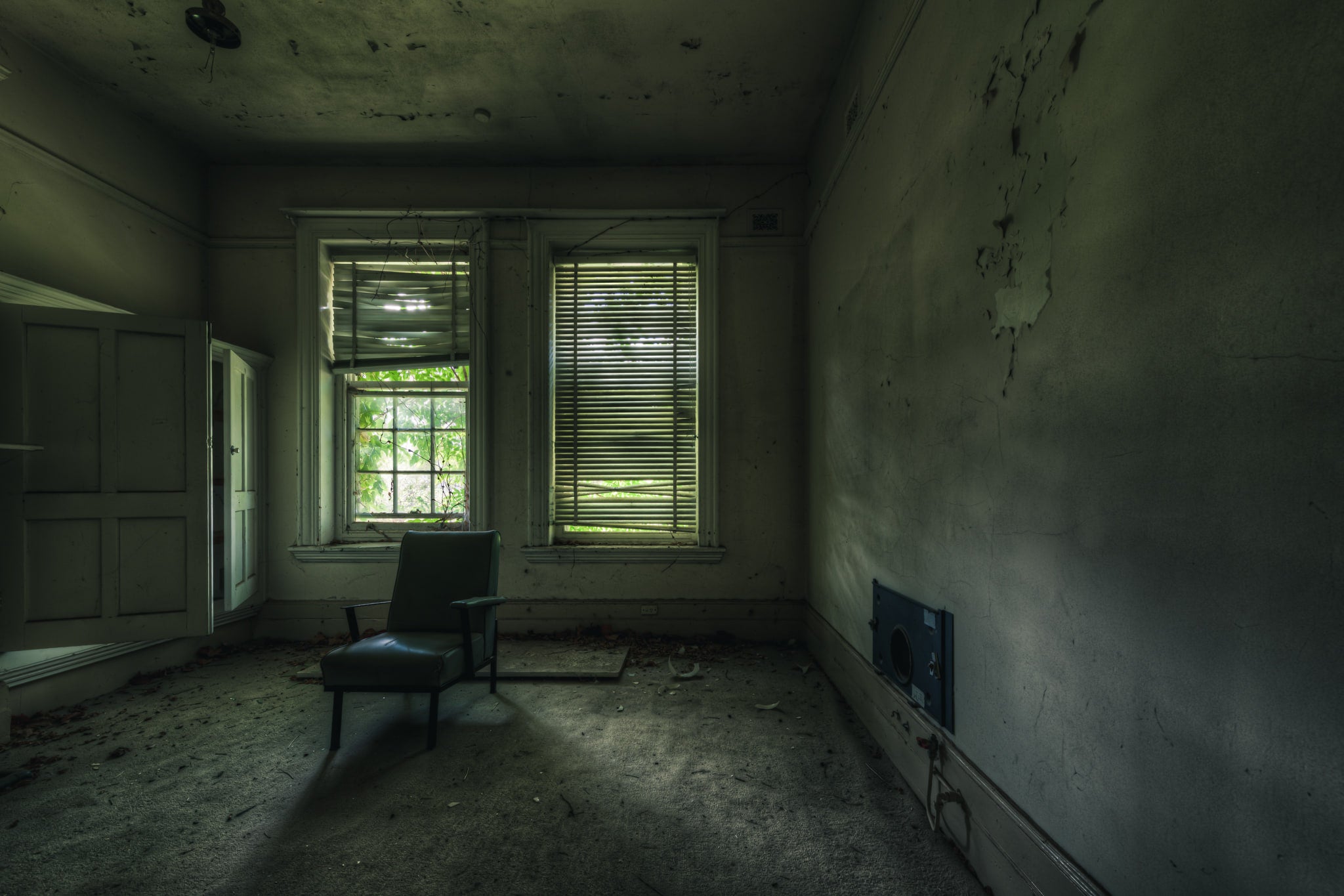 Slots of Light at The Asylum, a single vinyl chair sits near two windows in an otherwise empty room.