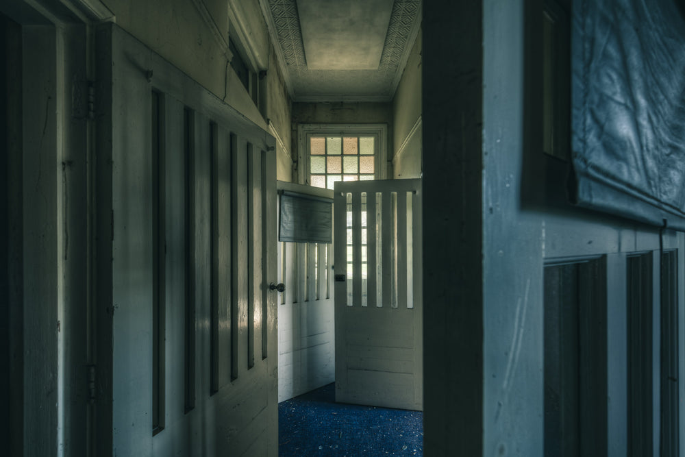 Slotted Doors at The Asylum, a narrow corridor lined with tall timber doors, each cut with vertical slotted openings.