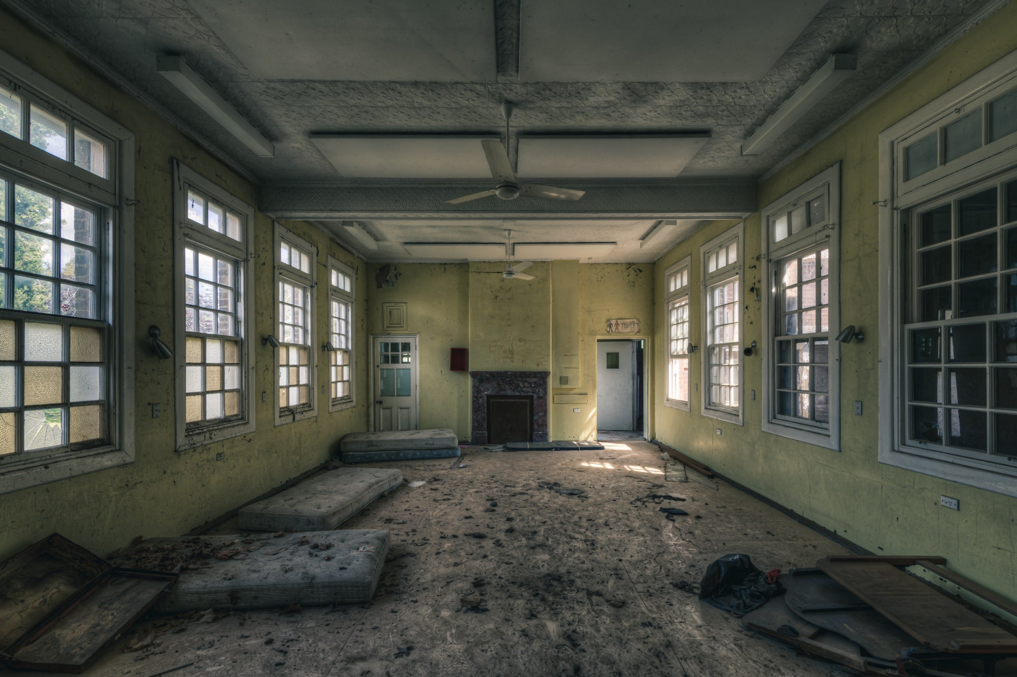 Spare Beds at The Asylum, a large common room with pale yellow walls and white-trimmed windows on three sides.