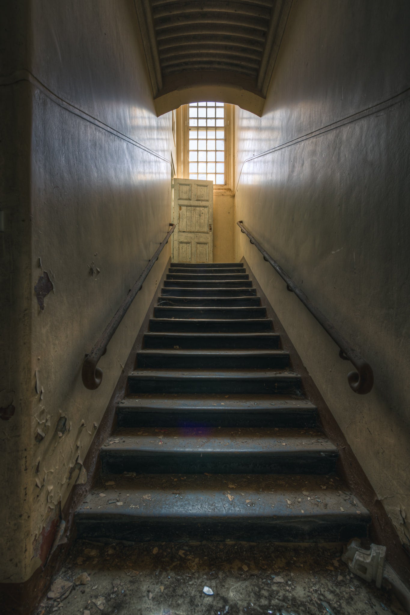 Stairs Up at The Asylum, a narrow stairwell climbs steeply between close walls.