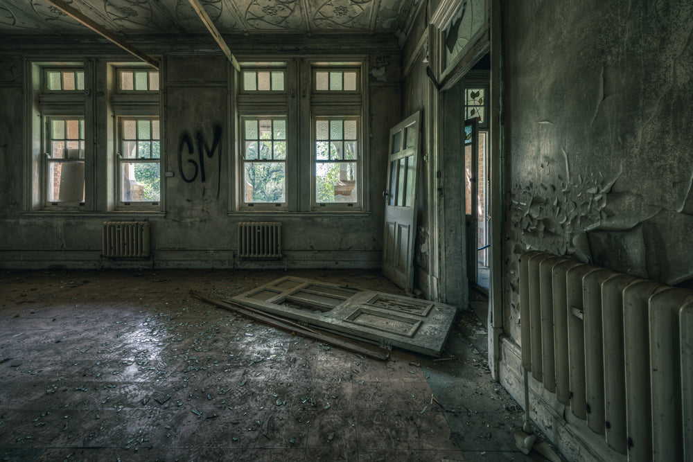 The Back Residence at The Asylum, a panelled door lies flat on the floor, torn from its hinges.