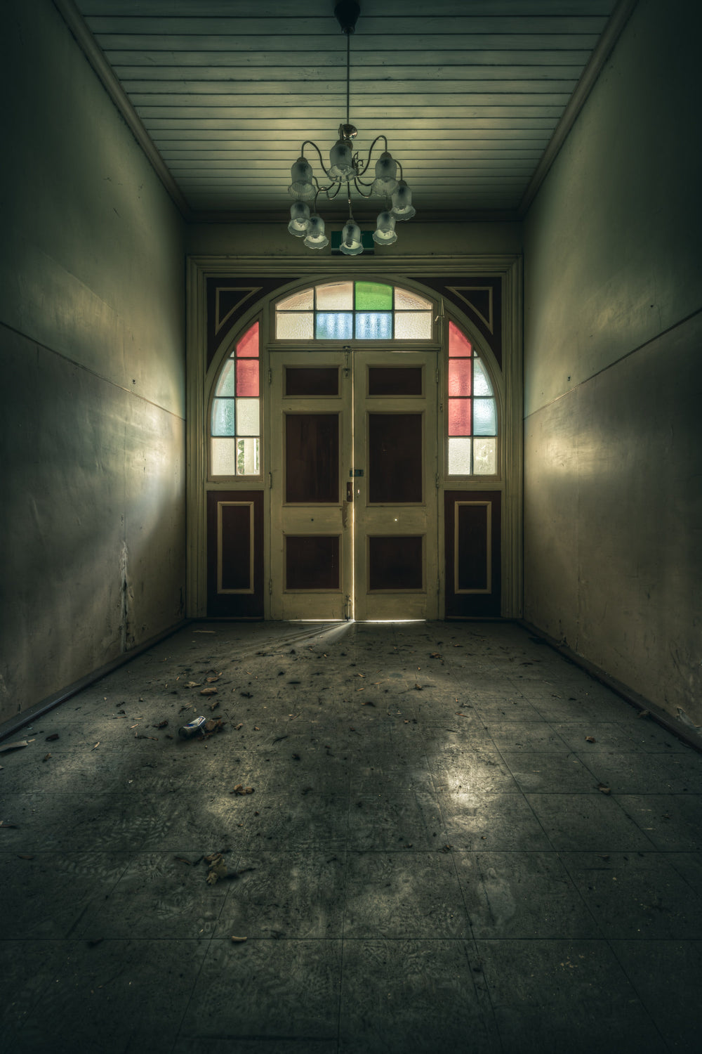 The Grand Entrance at The Asylum, a narrow entrance hall opens toward double timber doors set within an arched frame.
