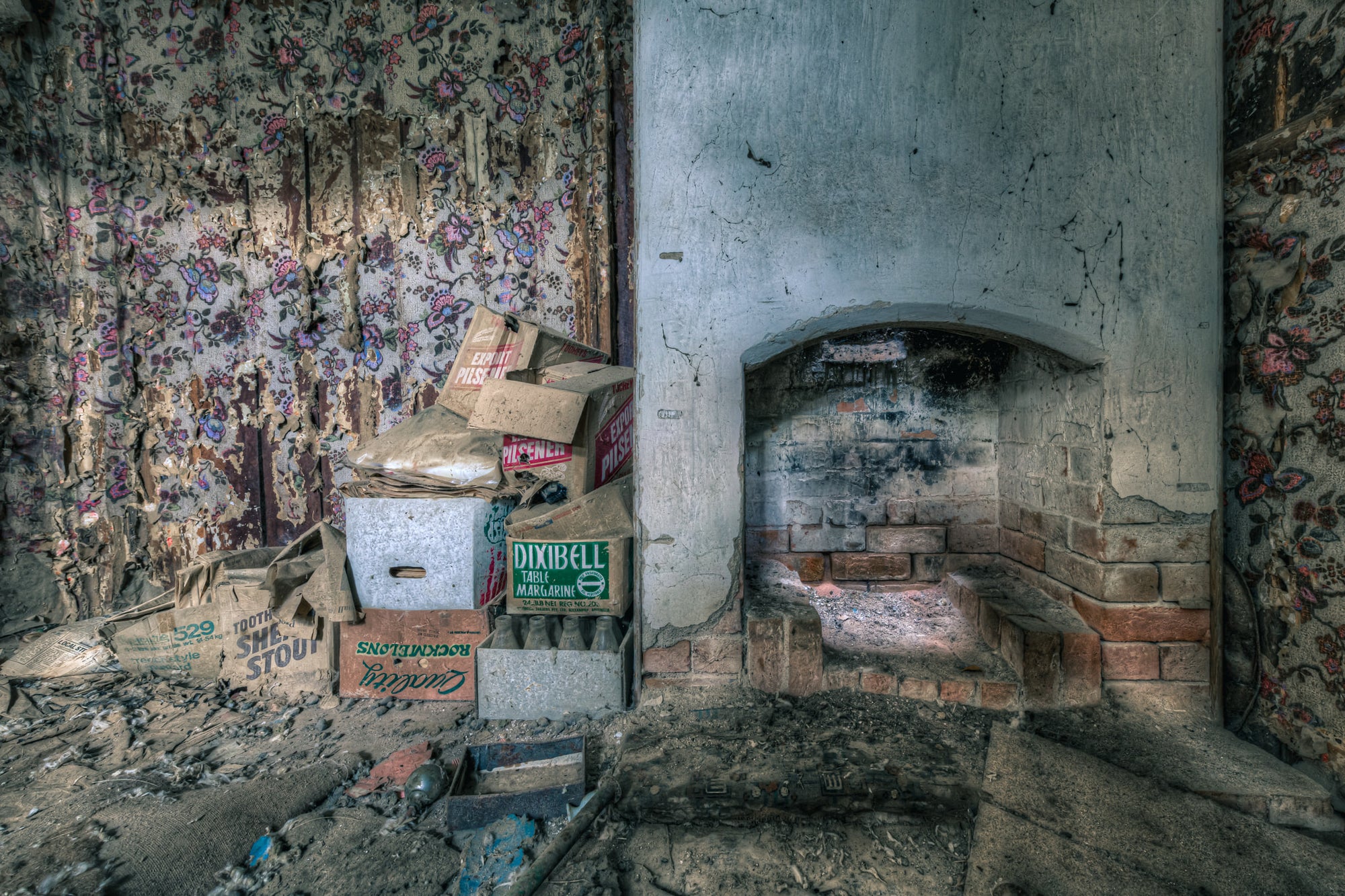 Bedroom Chimney at The Post Office, floral wallpaper peels from both walls in long vertical strips, exposing bare plaster.