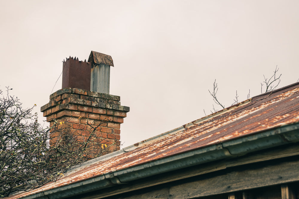 Chimneys at The Post Office, a brick chimney rises from the roofline, its mortar cracked and lichen-spotted.