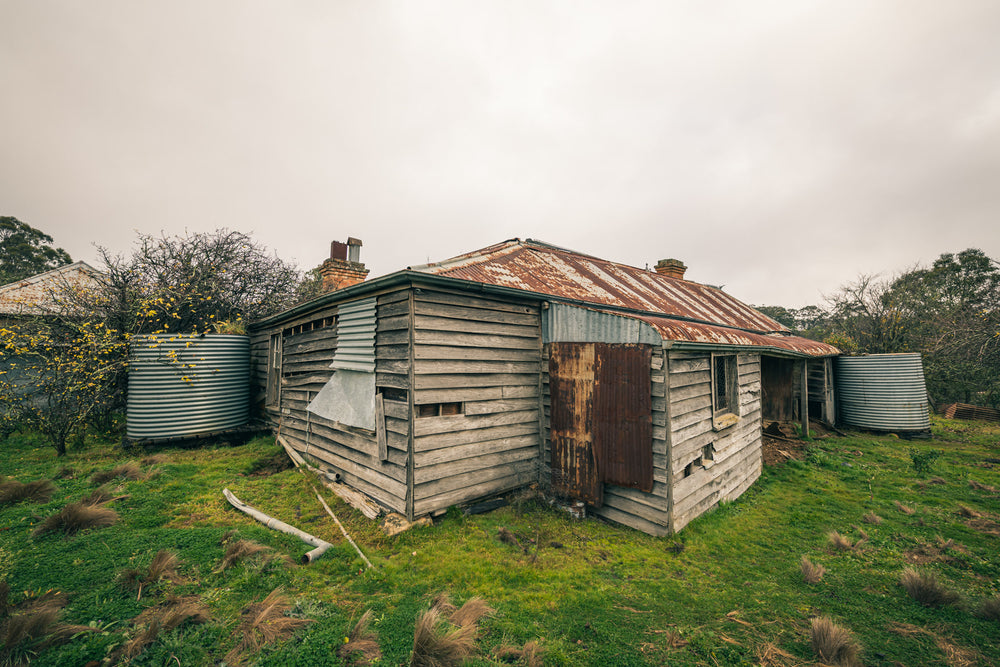 Postmasters Corner at The Post Office, weathered hardwood clapboards, grey and splintered, wrap a low cottage.