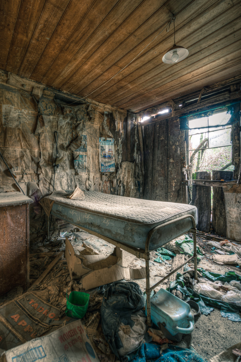 Smaller Bedroom at The Post Office, a single bed frame sits raised on metal legs, its stained mattress still intact.