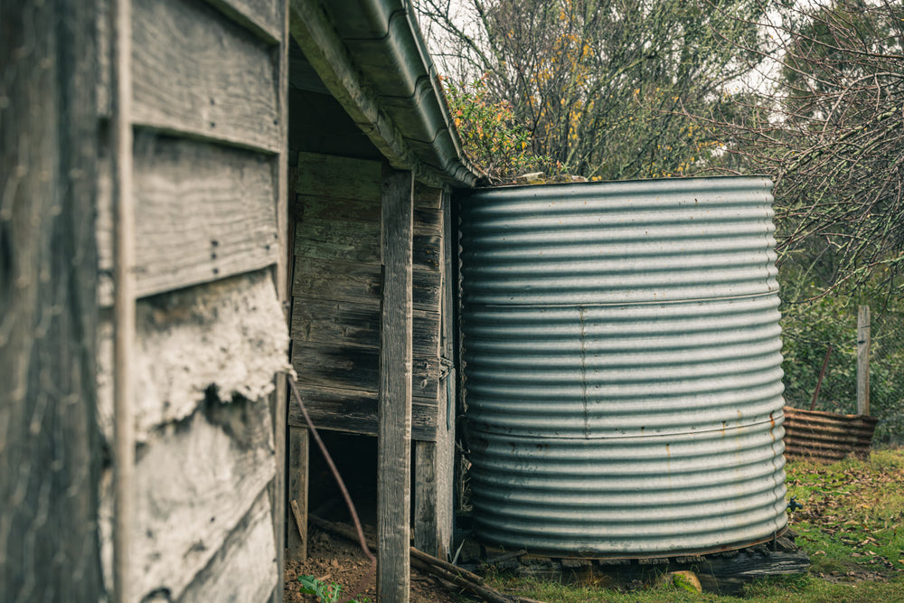 Water Tank at The Post Office, a corrugated steel water tank sits tight against the back corner of a timber outbuilding.