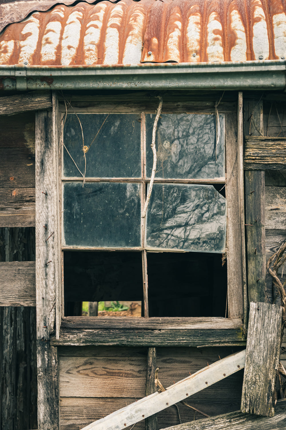 Window Panes at The Post Office, a six-pane timber window set into weatherboard cladding, grey and split with age.