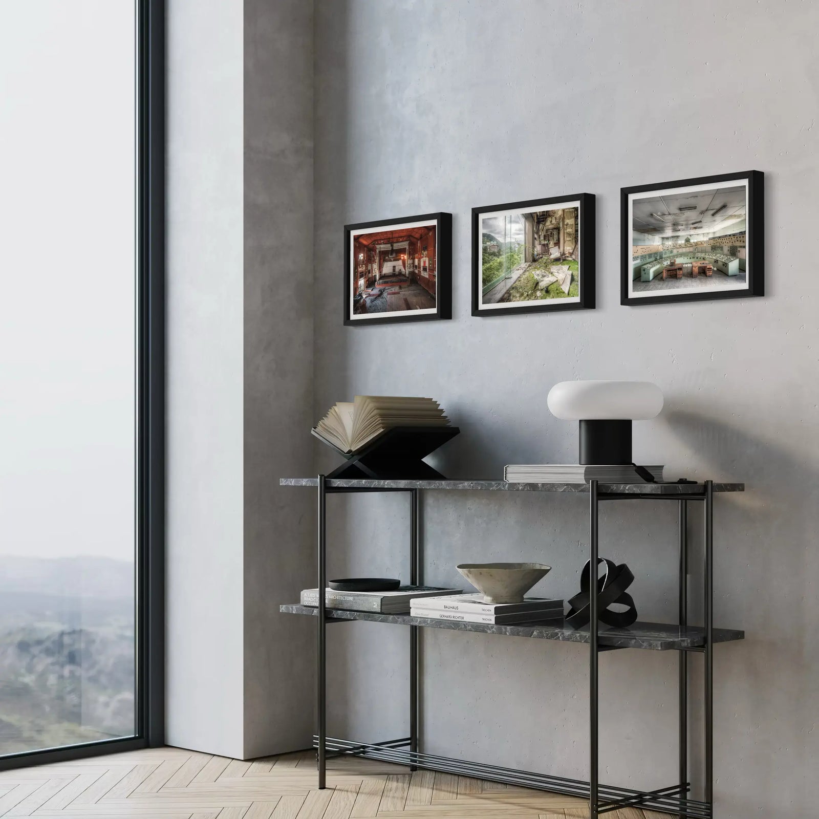 Three framed art prints depicting abandoned spaces and rural decay, styled with modern decor on a console shelf by a window.