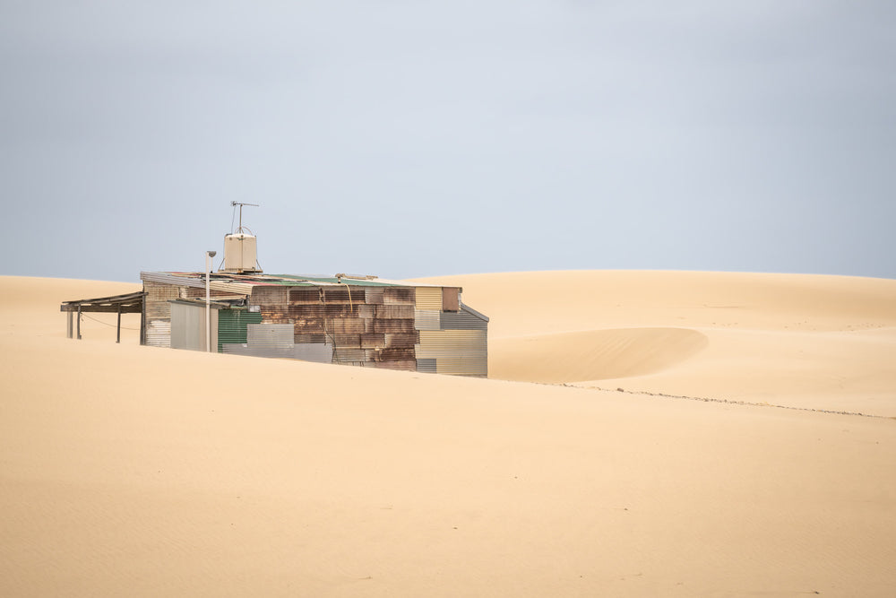 Buried at Tin City, a Tin City shack, recessed in rolling dunes of sand.