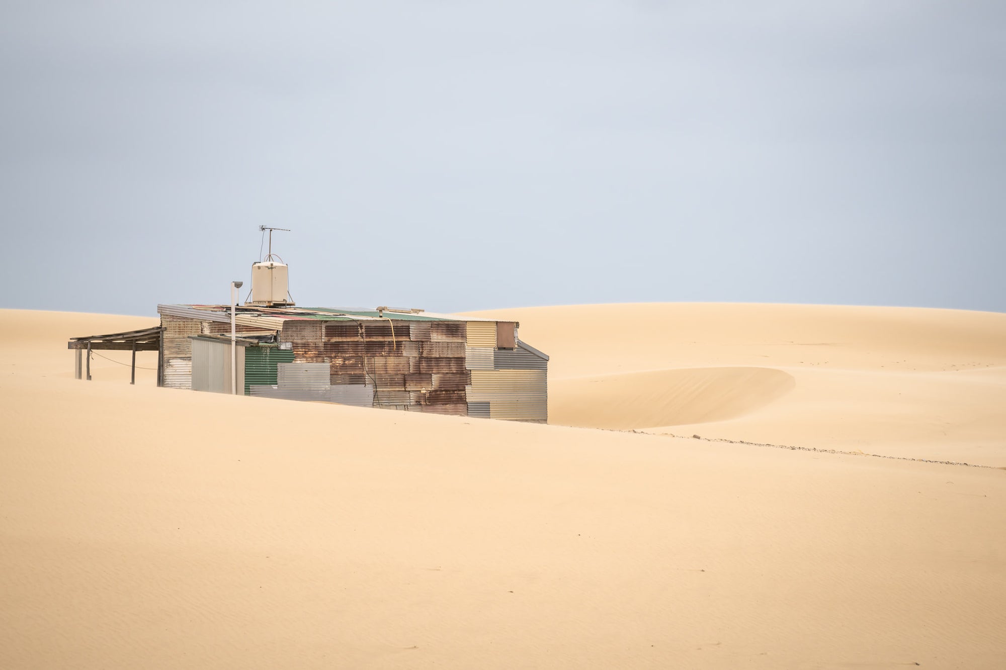 Buried at Tin City, a Tin City shack, recessed in rolling dunes of sand.