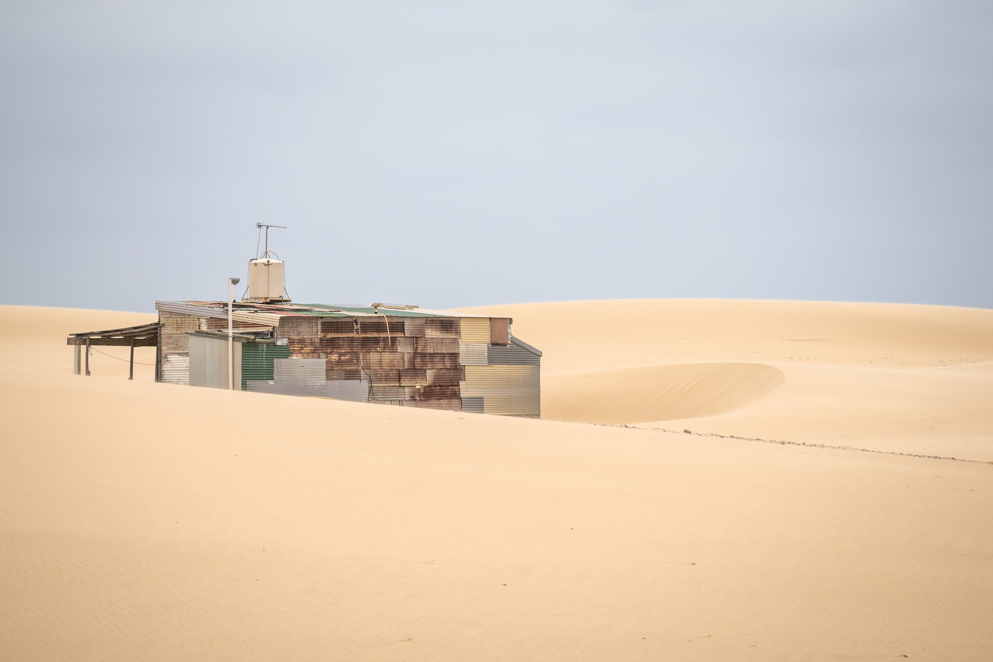 Buried at Tin City, a Tin City shack, recessed in rolling dunes of sand.