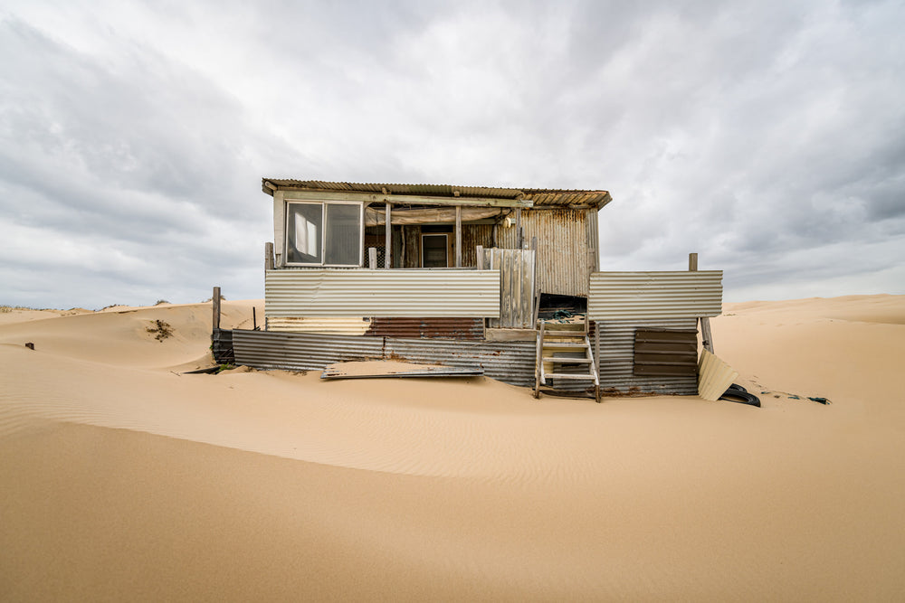 Eleven at Tin City, clean lines in a sandy foreground before a weathered Tin City shack.