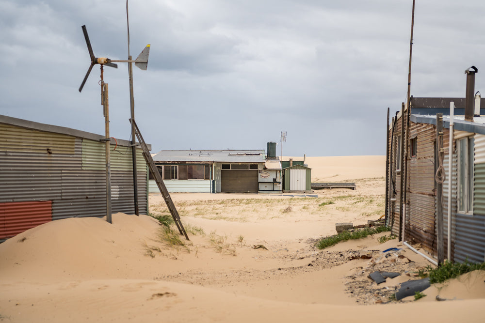 Facing South at Tin City, sand drifts between corrugated iron shacks, banking up against walls and burying the base.