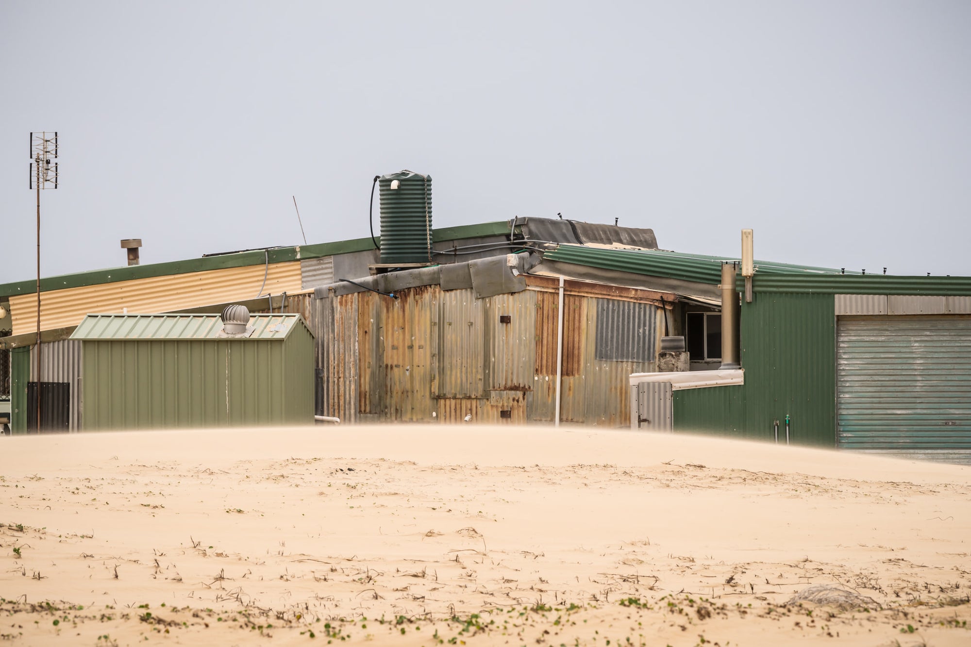 Patchwork at Tin City, green and rust-brown corrugated iron panels sit side by side across a long, low structure.