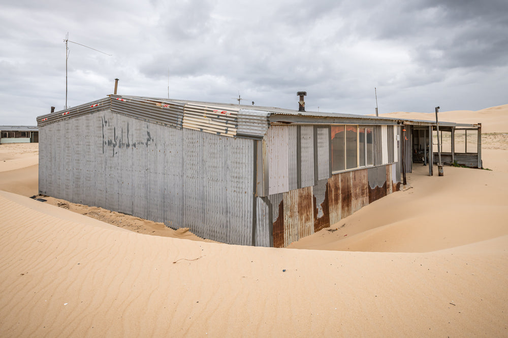 Recess at Tin City, sand banks hard against corrugated iron walls, rising halfway up the structure.